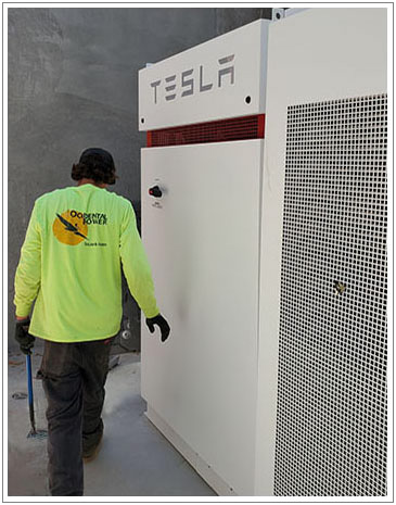 Occidental Power tradesman next to solar storage battery by Tesla